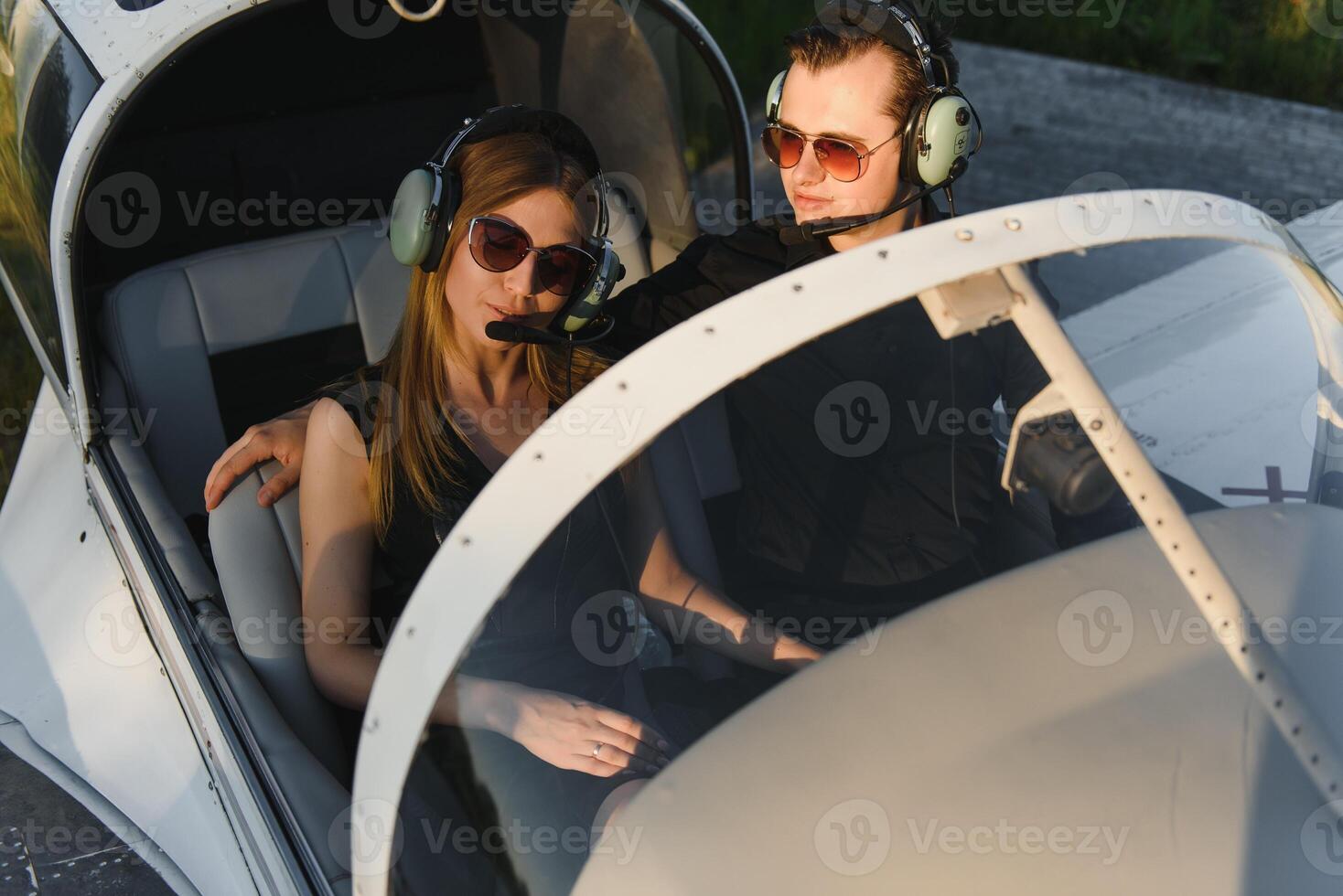 Young woman and pilot in in the cockpit of a plane. Front view photo