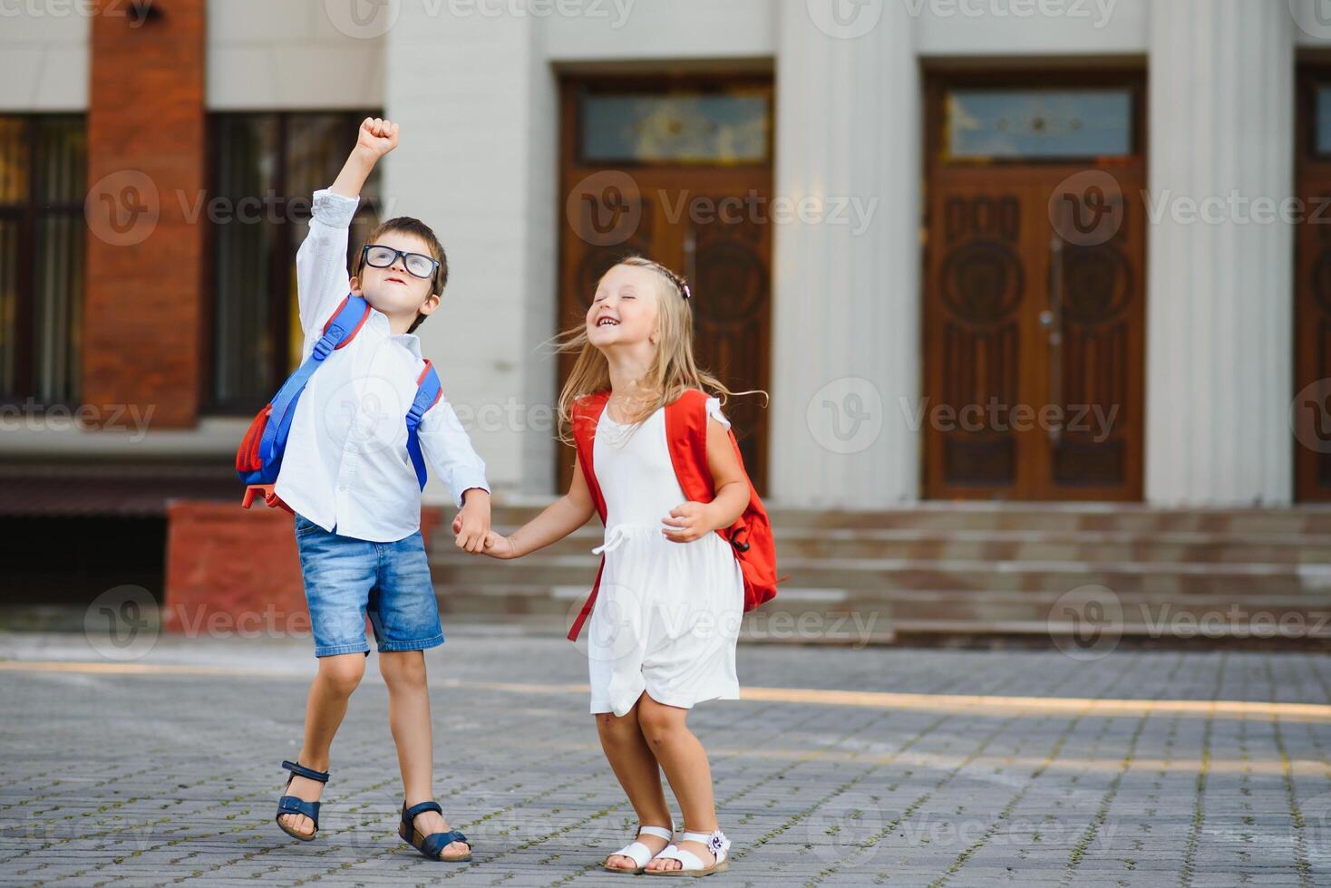 Happy children go back to school. Pupil of primary school go study with backpack outdoors. Kids go hand in hand. Beginning of lessons. First day of fall. Boy and girl from elementary student. photo