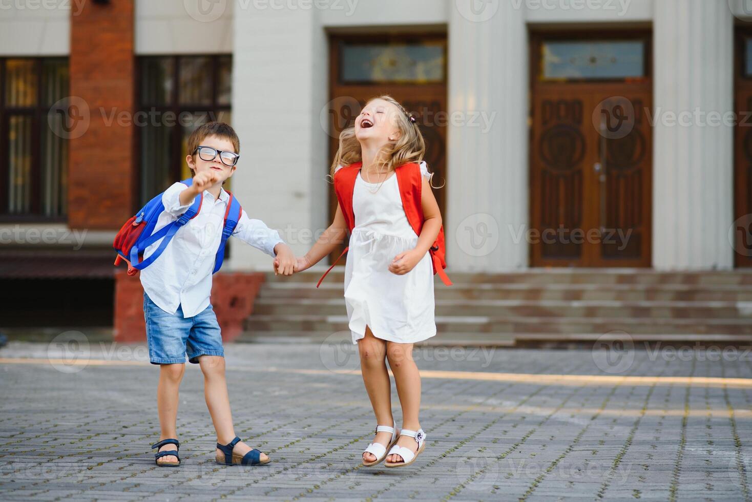 Happy children go back to school. Pupil of primary school go study with backpack outdoors. Kids go hand in hand. Beginning of lessons. First day of fall. Boy and girl from elementary student. photo