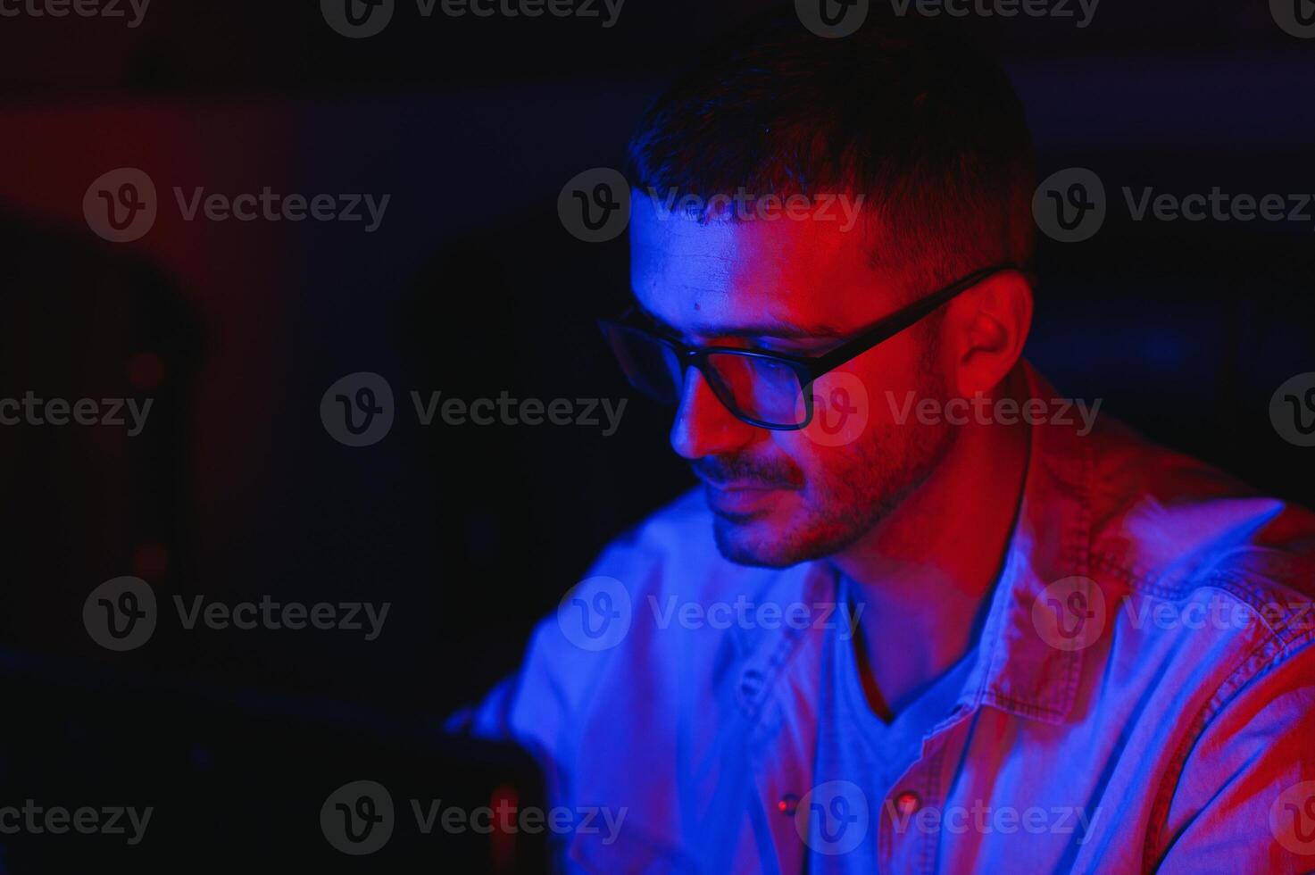 Pro Gamer. Millennial Guy Using Desktop Computer Playing Online Videogame Sitting At Night At Home. Neon Lights, Selective Focus photo