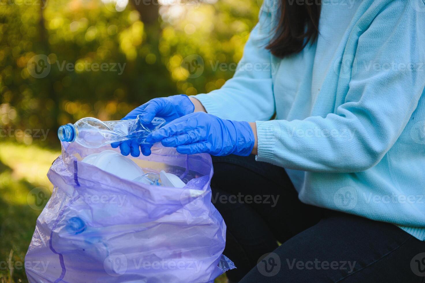 hand puts plastic debris in the garbage bag in the park photo