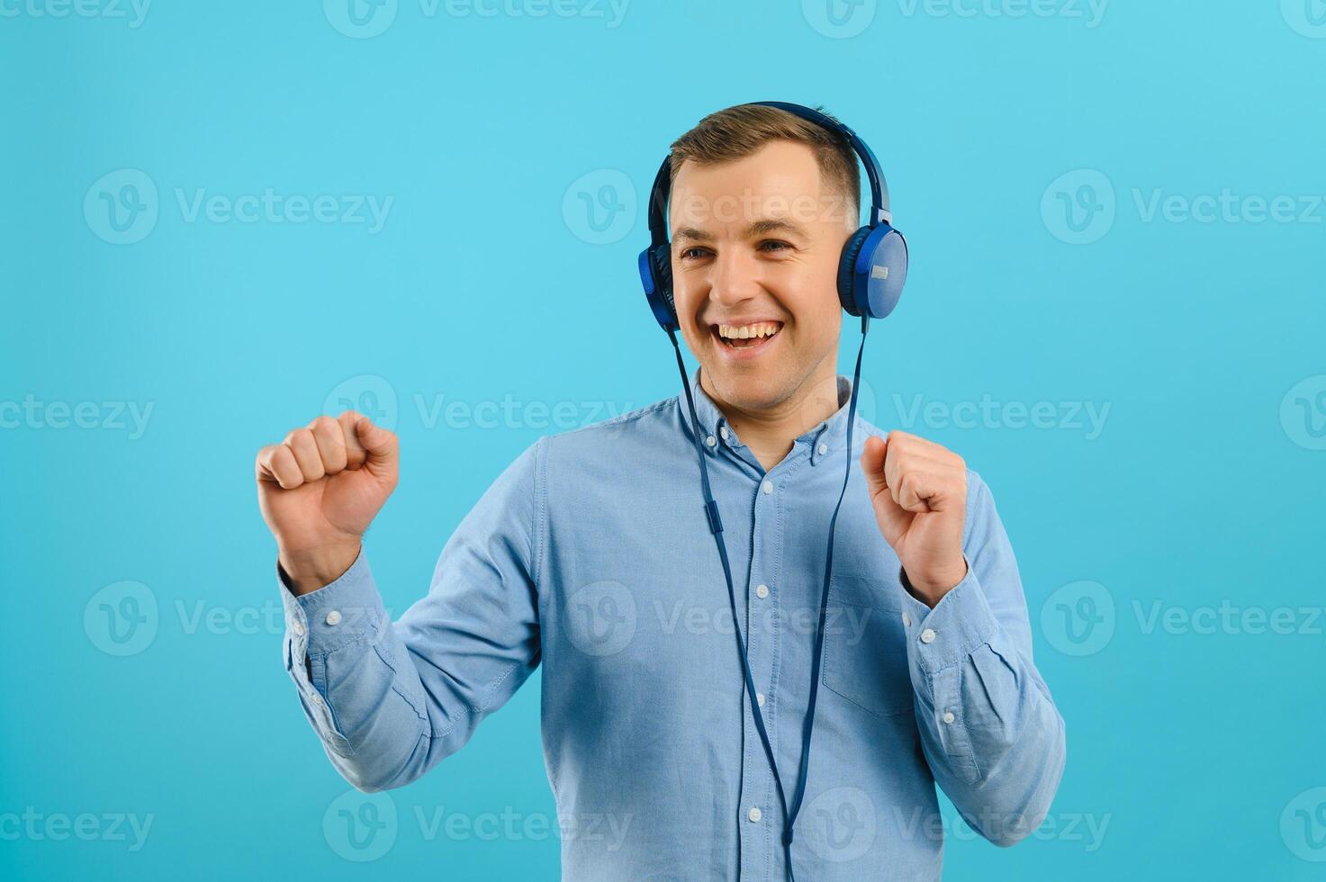 Handsome young man posing on color background. Young smiling man listening to music on headphones. photo