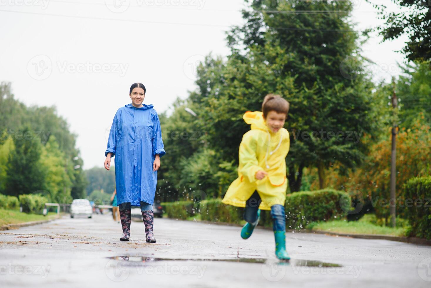 Mom and son in raincoats have fun together in the rain. concept of family vacation and happy childhood. photo