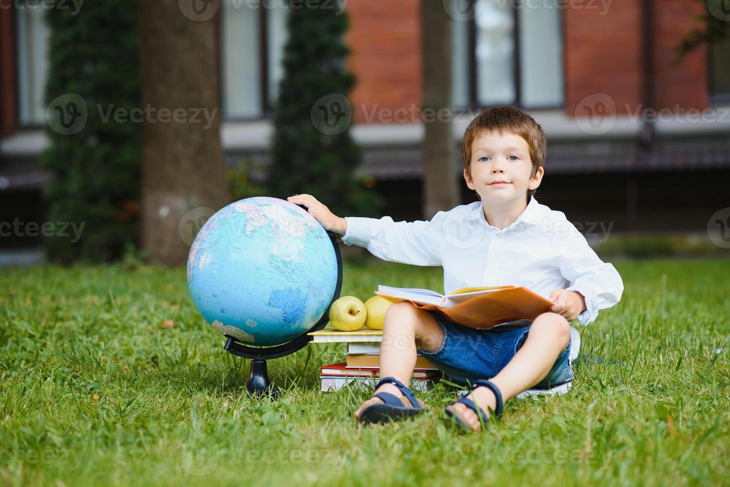 Pupil near school. Boy sitting with a book. photo