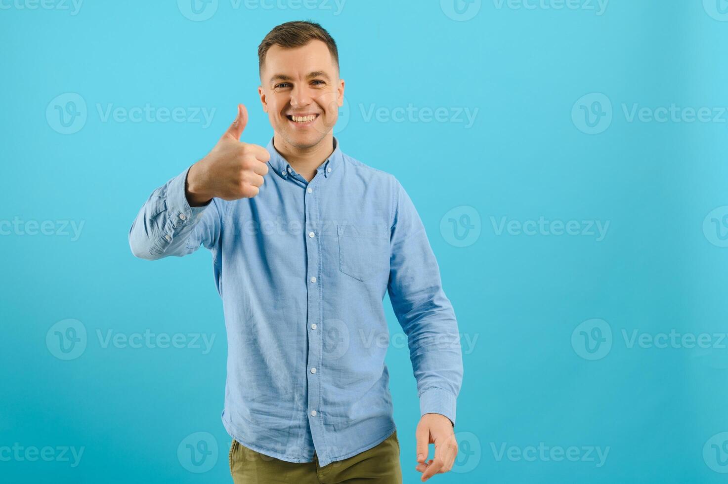 Happy smiling handsome man in clothing, showing copy space, visual imaginary or something, or pressing virtual button, aqua marine blue color background. photo