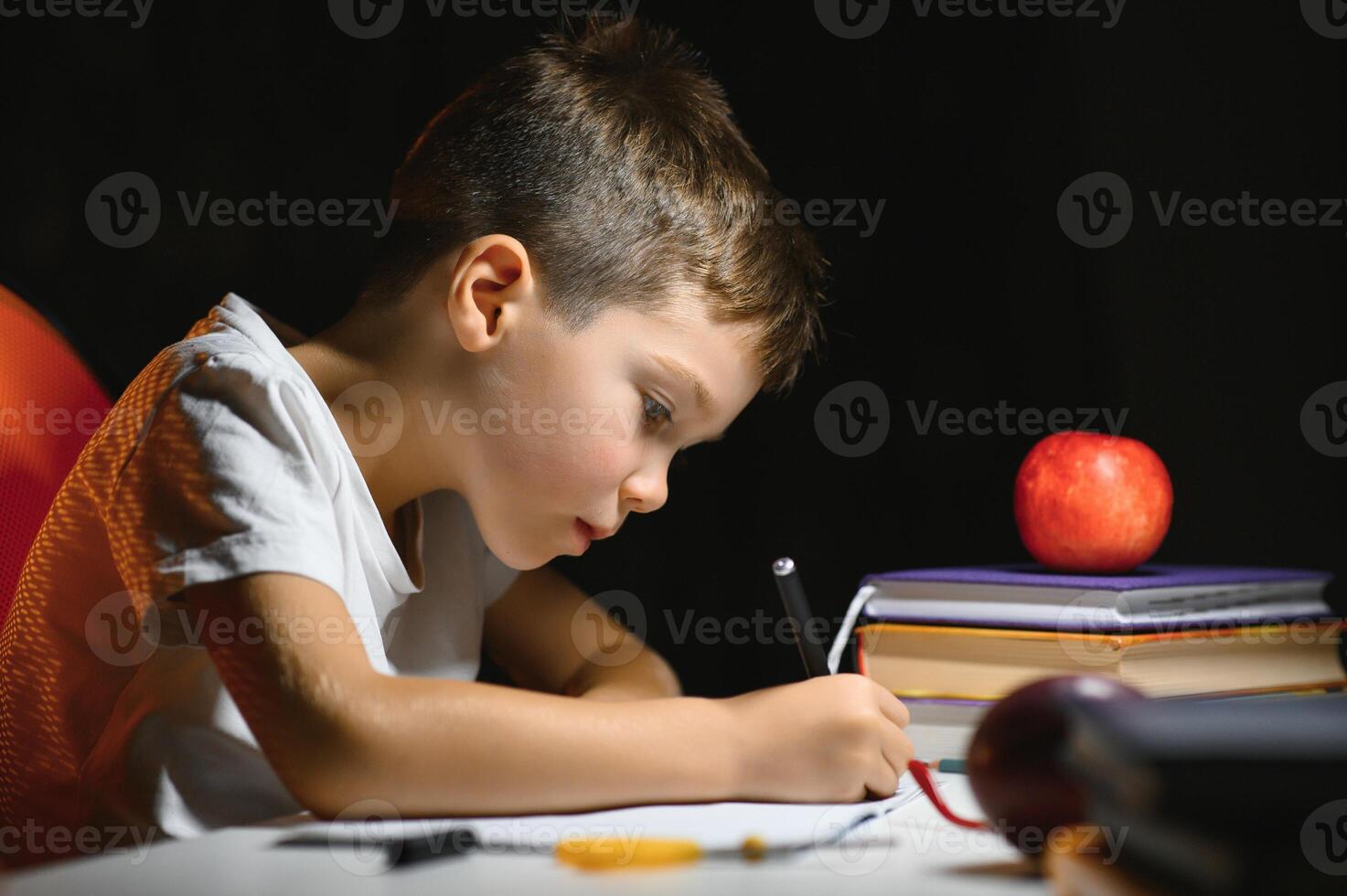 Boy learn lessons in the home setting at the table in the light of a table lamp. photo