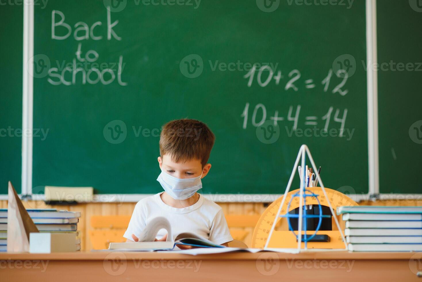 Schoolboy in the classroom in a protective mask. The concept of schooling during the epidemic photo