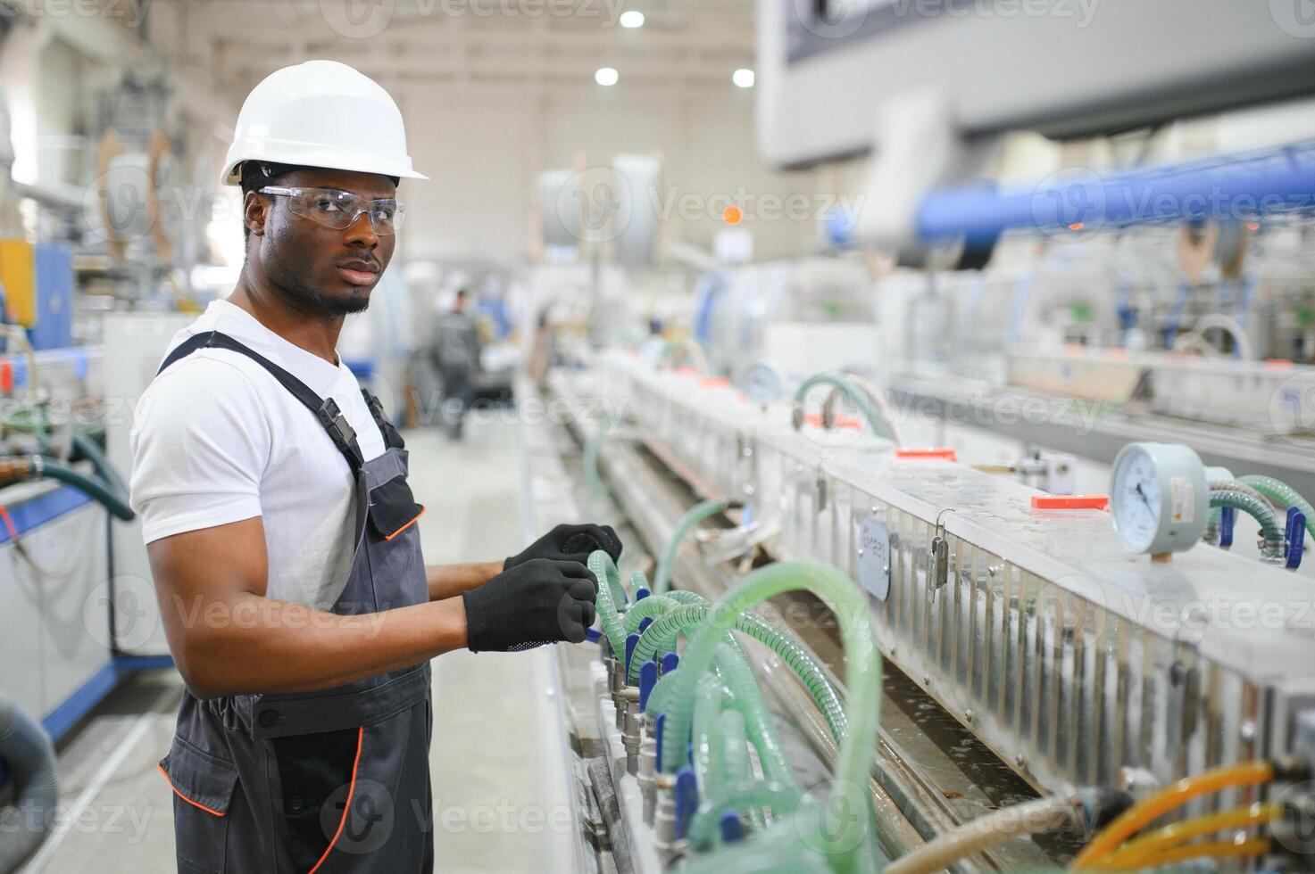 Portrait of industrial engineer. Smiling factory worker with hard hat standing in factory production line photo