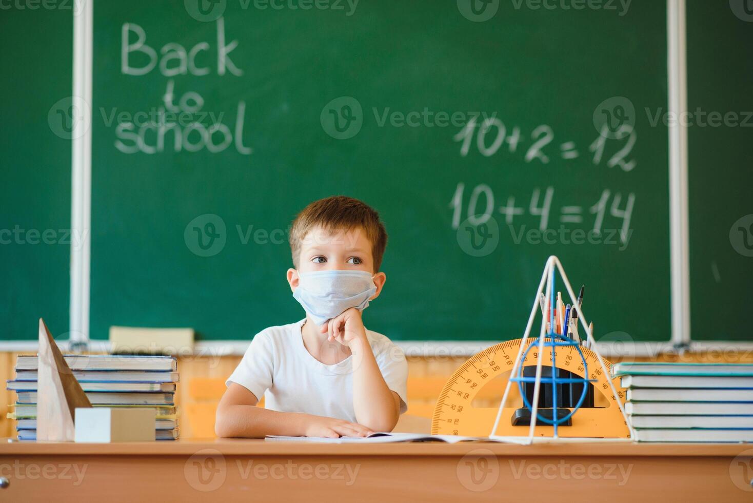 Schoolboy in the classroom in a protective mask. The concept of schooling during the epidemic photo
