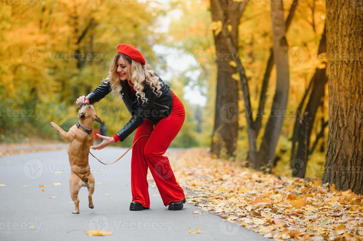 Beautiful and happy woman enjoying in park walking with her adorable French bulldog. photo