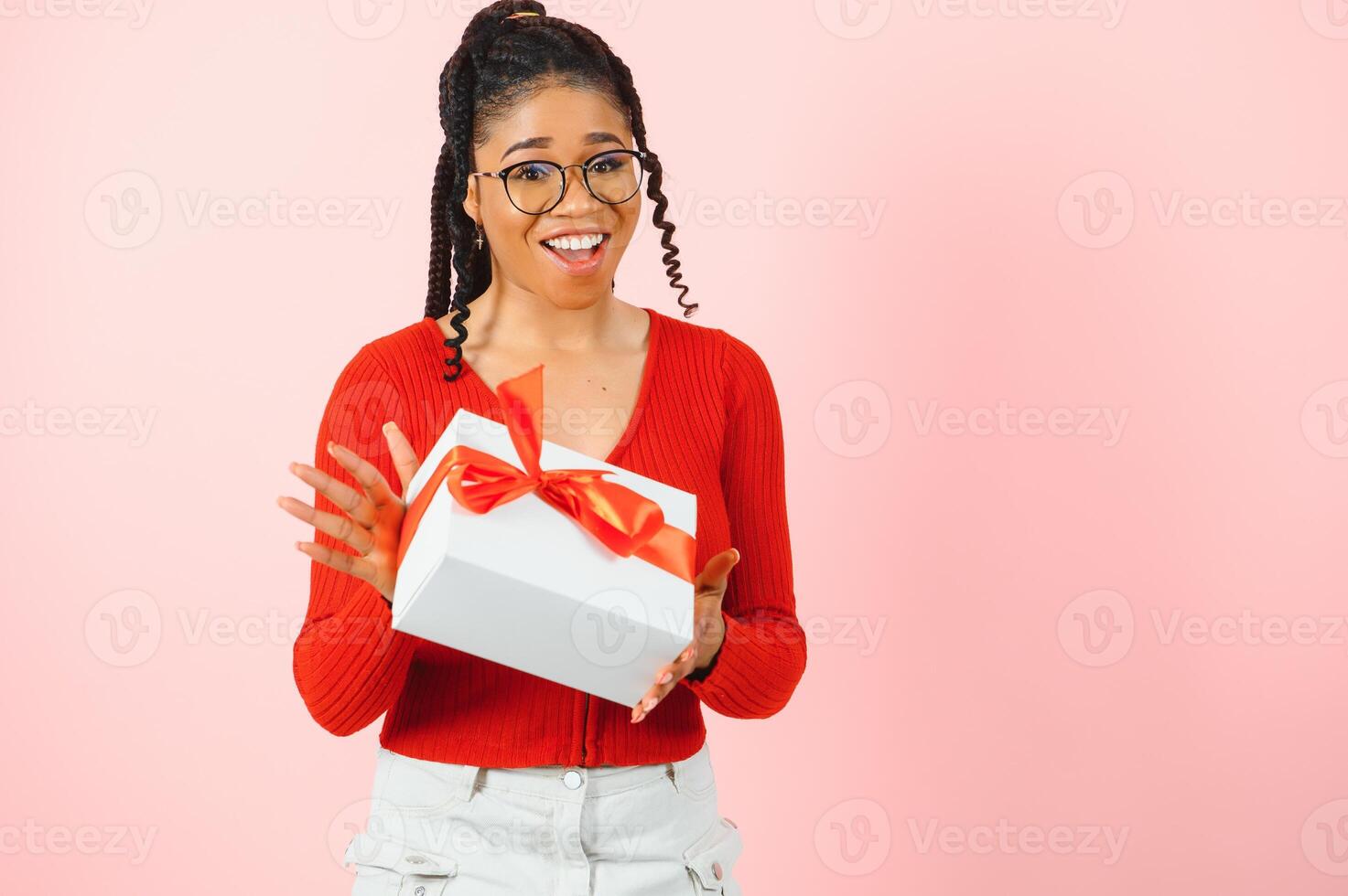 foto retrato de emocionado mujer participación regalo caja en dos manos aislado en pastel rosado de colores antecedentes.