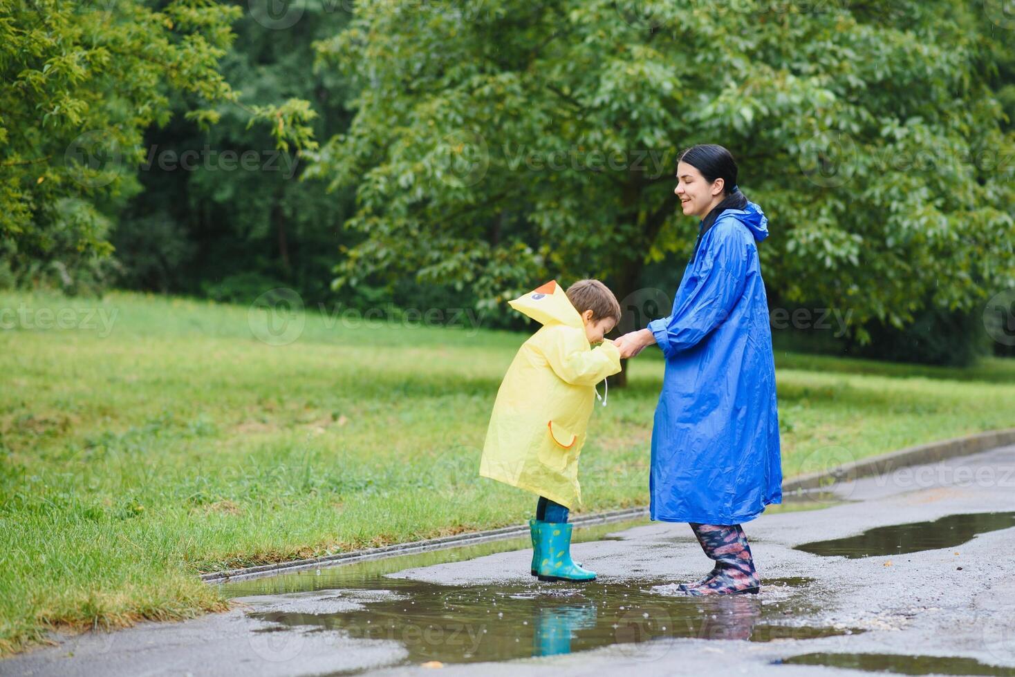 Mom and son in raincoats have fun together in the rain. concept of family vacation and happy childhood. photo