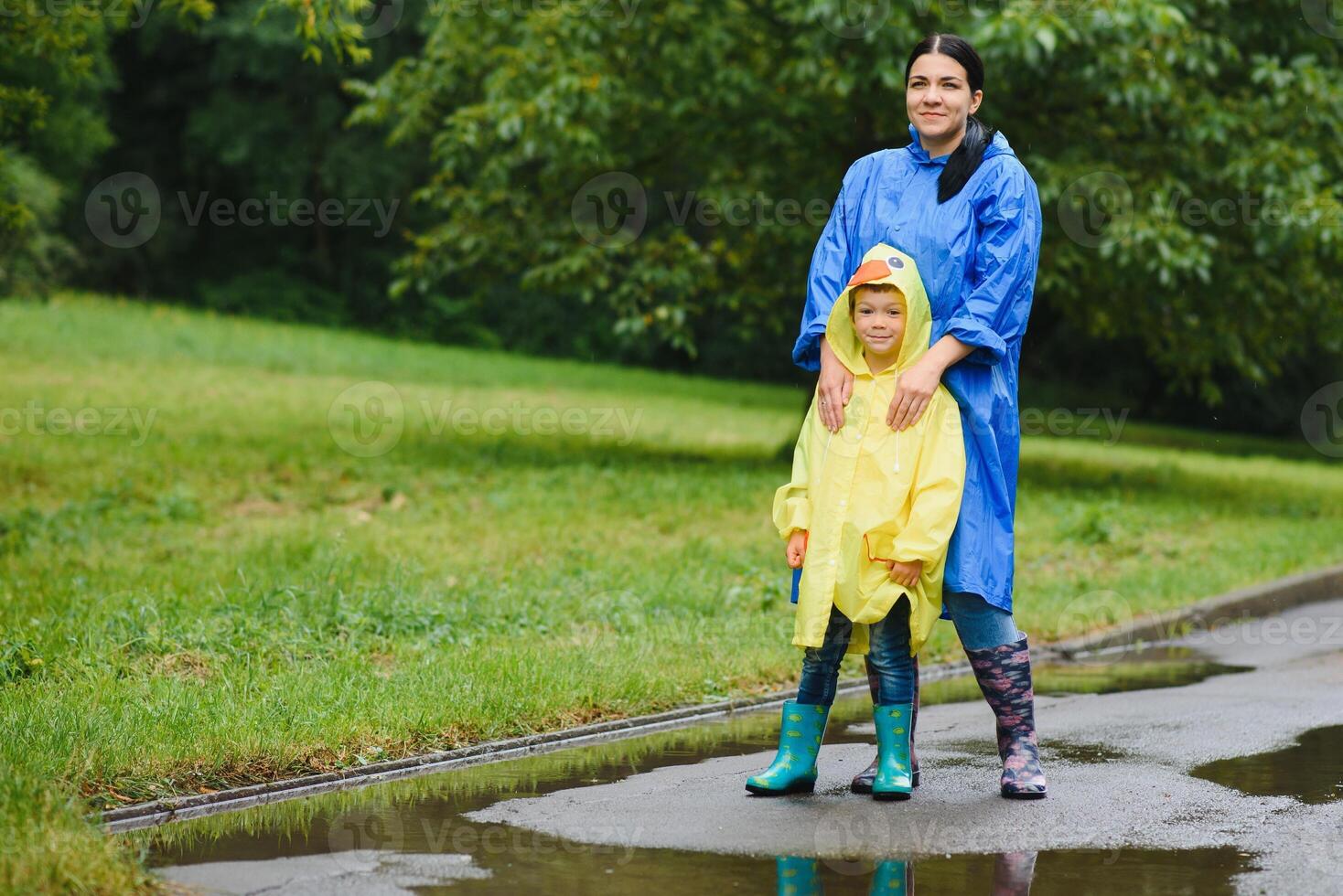 Mother and child, boy, playing in the rain, wearing boots and raincoats photo