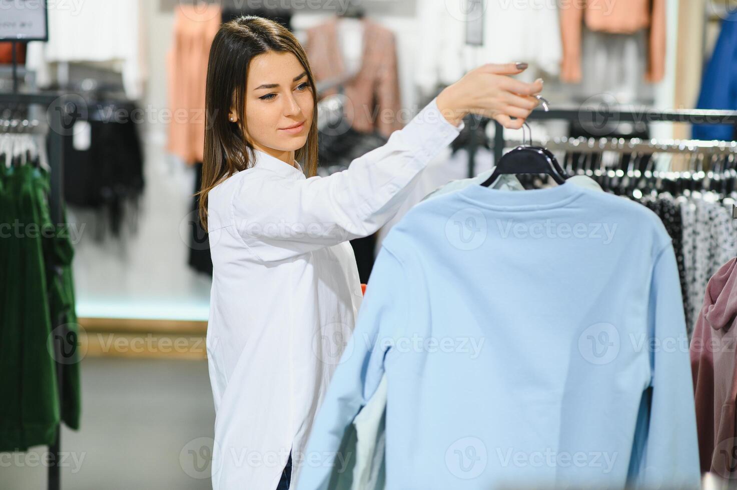 Girl is in modern store with new clothes. Elegant expensive wear. photo