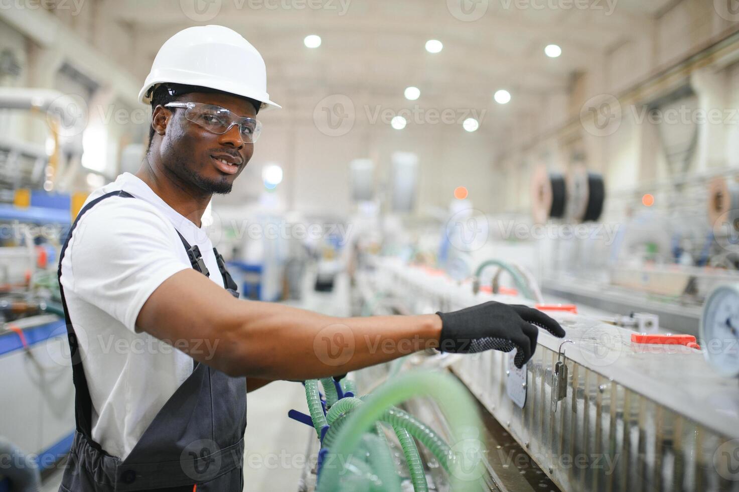 Industrial worker indoors in factory. Young technician with white hard hat photo