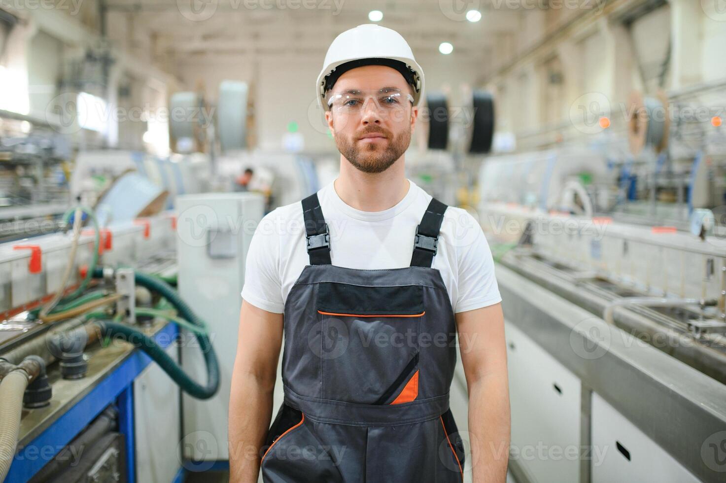 un masculino trabajador en un especial uniforme y un blanco casco. producción de marcos para cloruro de polivinilo ventanas foto