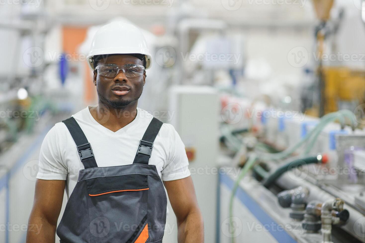 Portrait of industrial engineer. Smiling factory worker with hard hat standing in factory production line photo