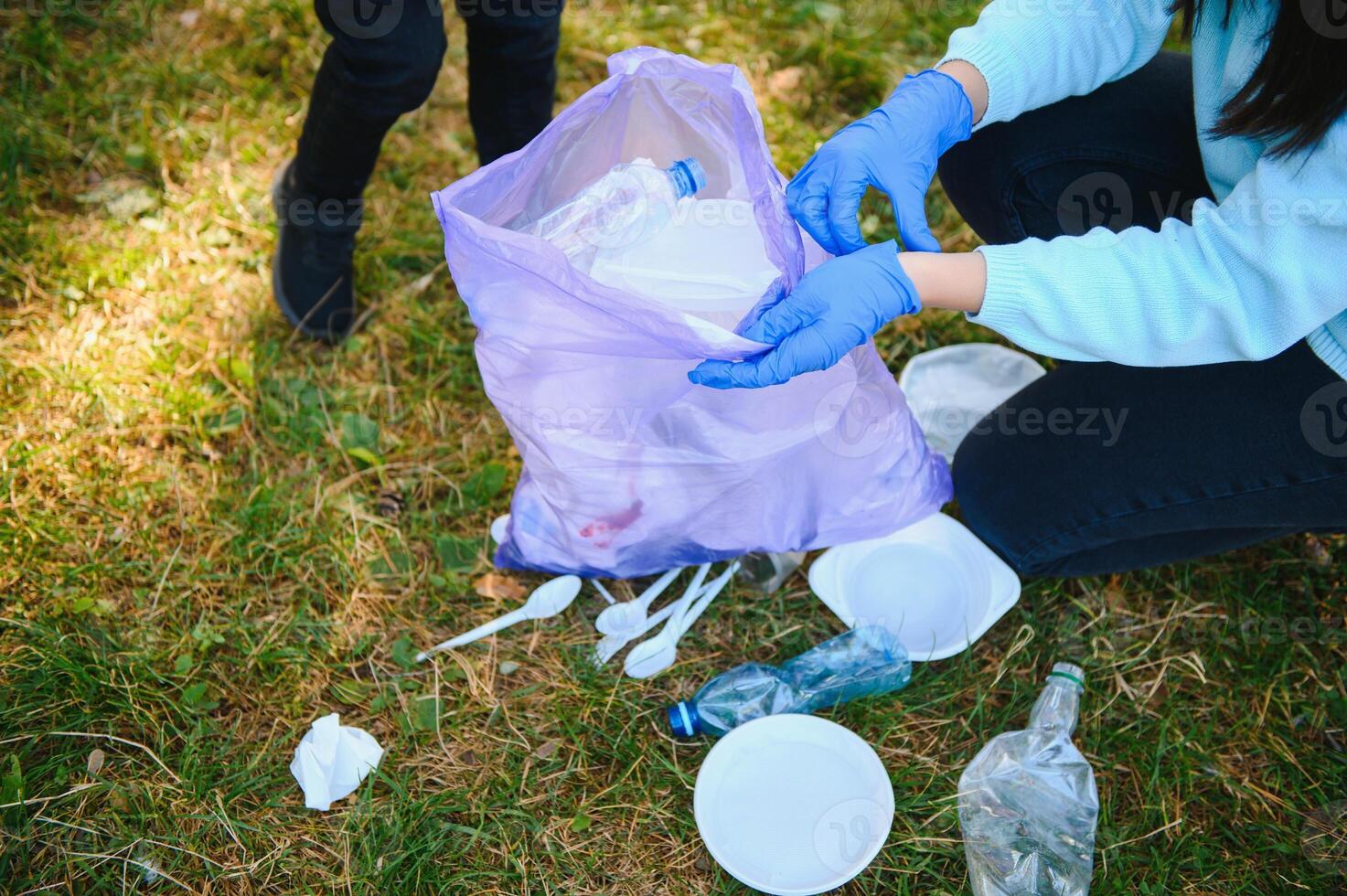 Smiling boy picking up trash in the park with his mother. Volunteer concept. photo