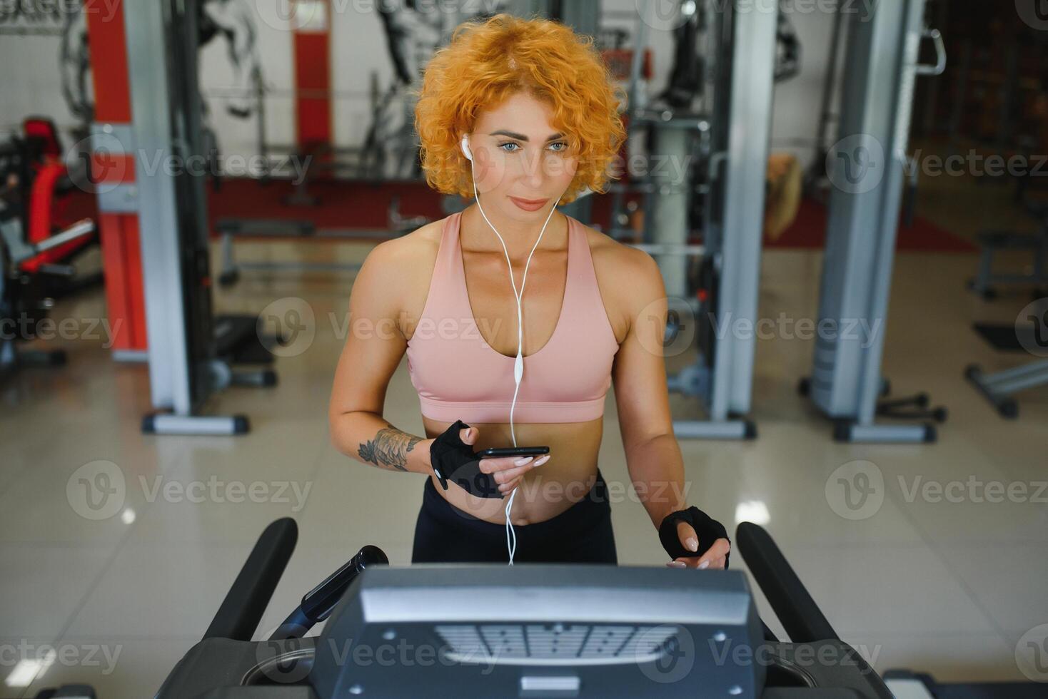 attractive young woman runs on a treadmill, is engaged in fitness sport club photo