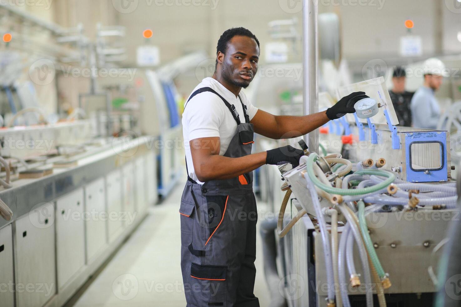 African male engineer. Control a material production machine system, working in a plastic and steel industry regarding the company's product business. photo