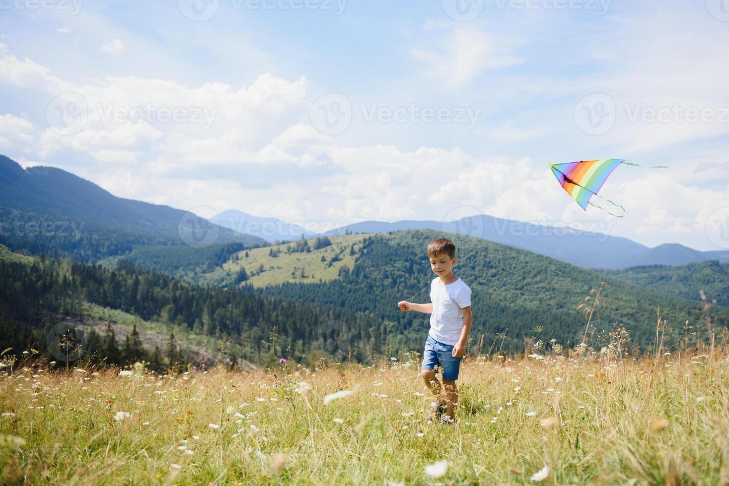 little boy holds string of kite flying in blue sky with clouds in summer with copyspace photo