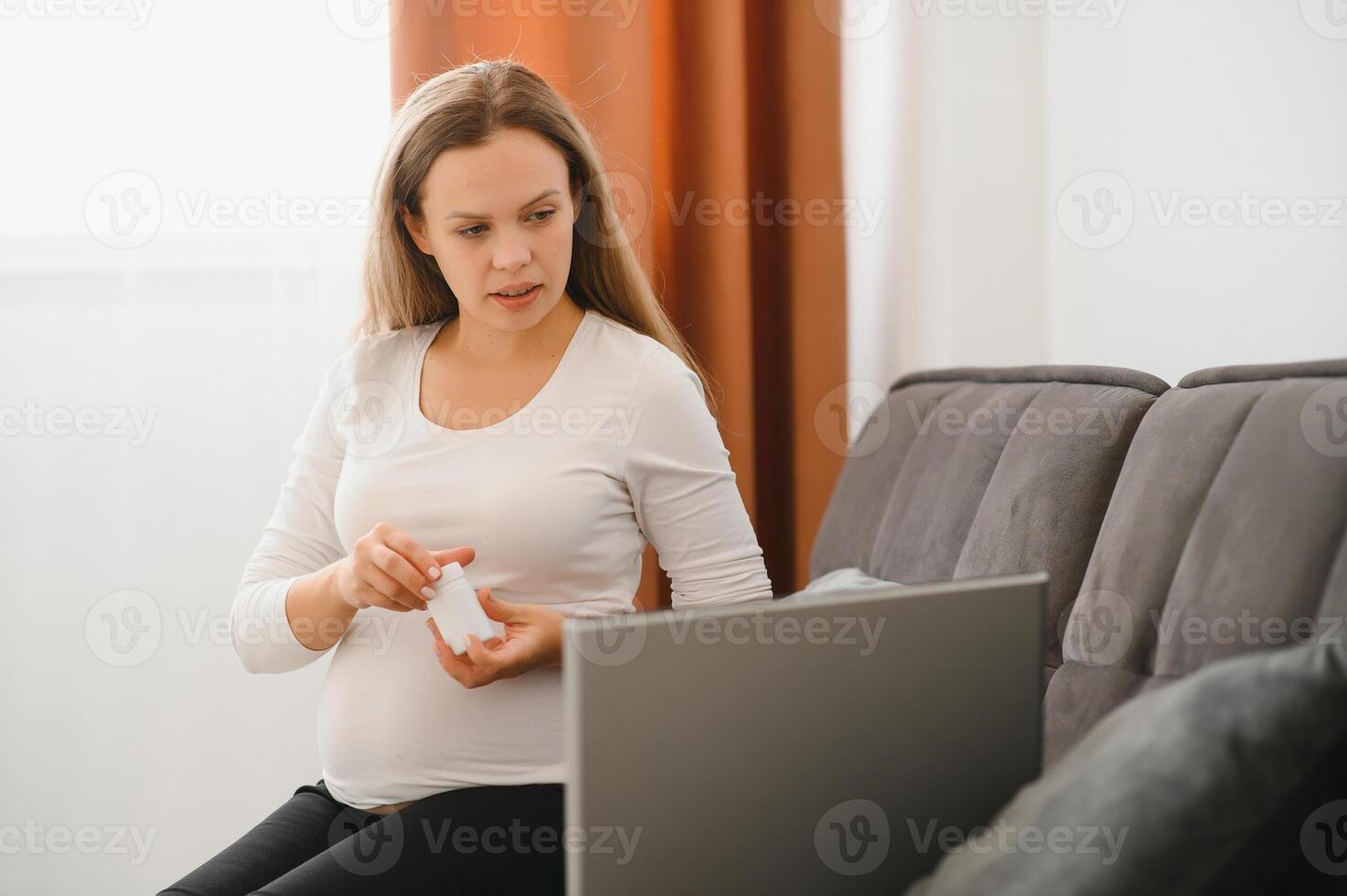 Pregnant woman video chatting with doctor on laptop. Professional medical online consultation concept. photo