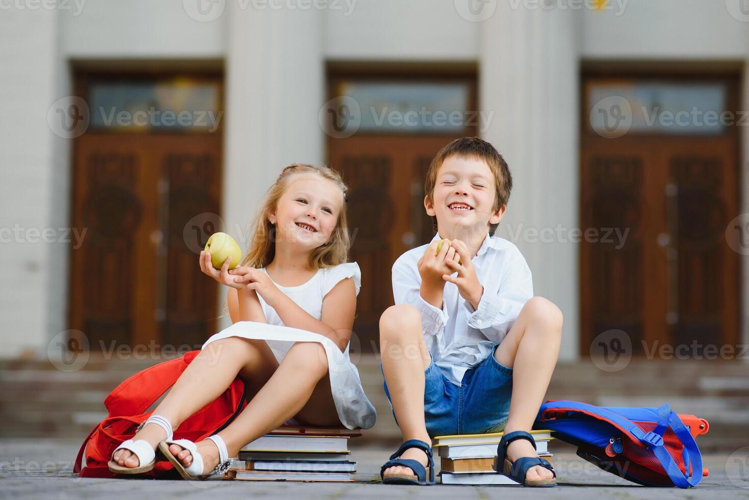 Happy children - boy and girl with books and backpacks on the first school day. Excited to be back to school after vacation. Full length outdoor portrait. photo