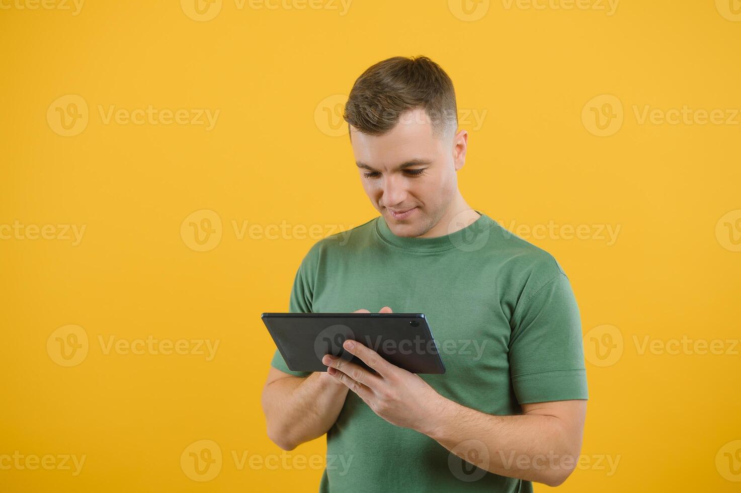 Amazed happy man using digital tablet looking shocked about social media news, astonished man shopper consumer surprised excited by online win isolated over yellow background. photo