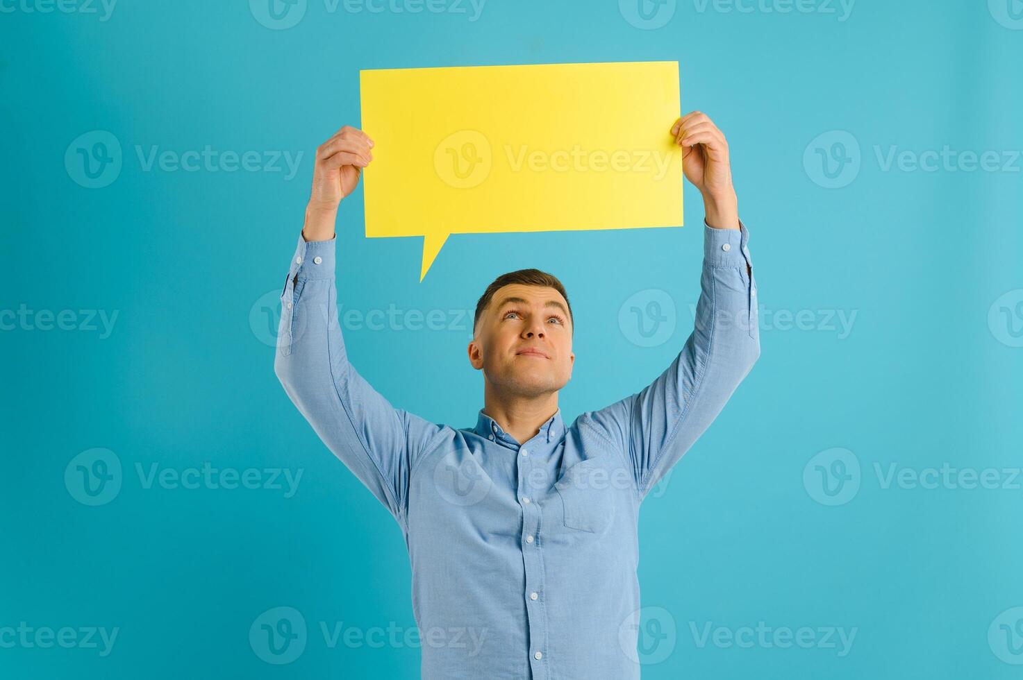 guy holding speech bubble on blue studio background, mockup for design photo