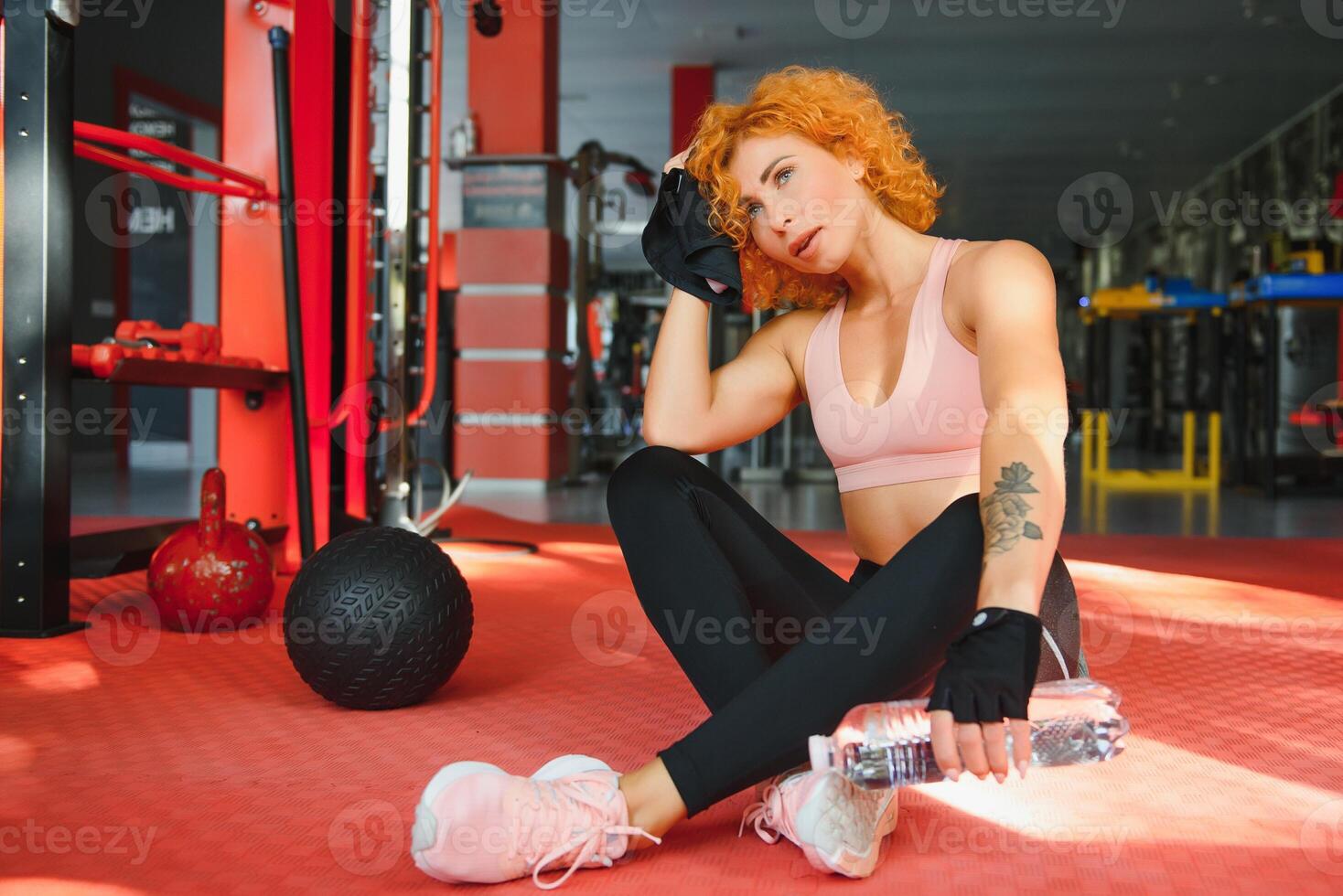 aptitud niña con fuerte cuerpo teniendo descanso Entre cardio ejercicio. deportivo mujer en Moda ropa de deporte descansando después intenso haciendo ejercicio ajuste hembra con muscular cuerpo mirando cansado. foto