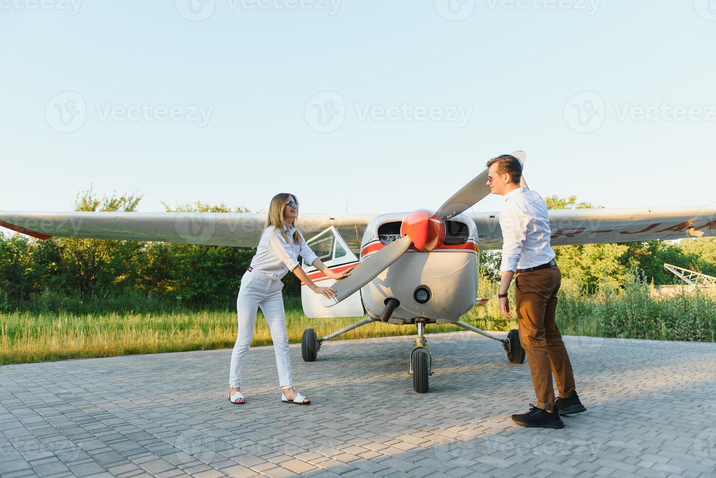 longitud total imagen de hermosa joven elegante Pareja cerca privado avión. caminando en pista en aeropuerto en frente de avión. foto