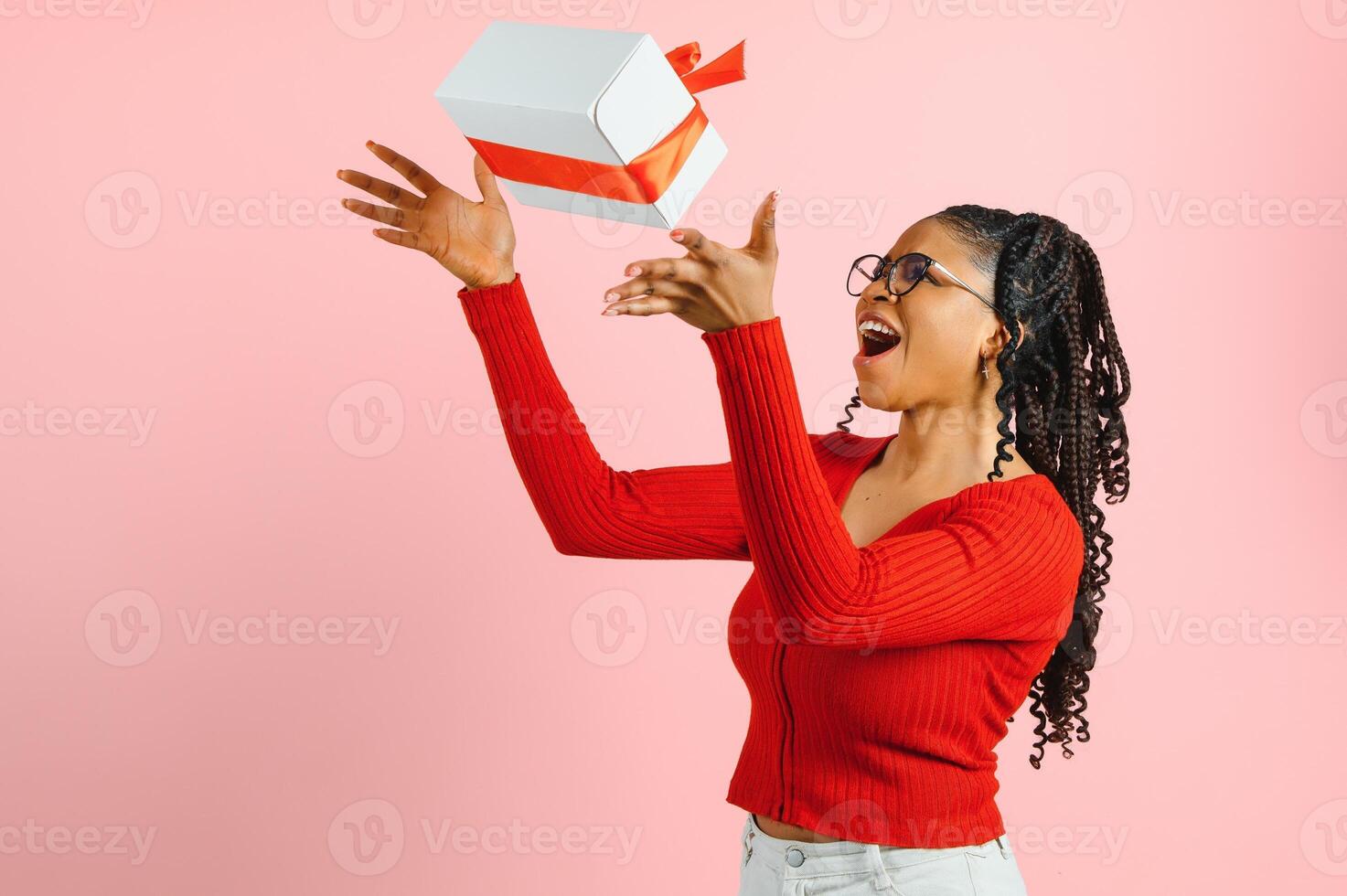 Portrait of pretty cheerful wavy-haired girl holding in hands giftbox congrats sale copy space isolated over pink pastel color background. photo