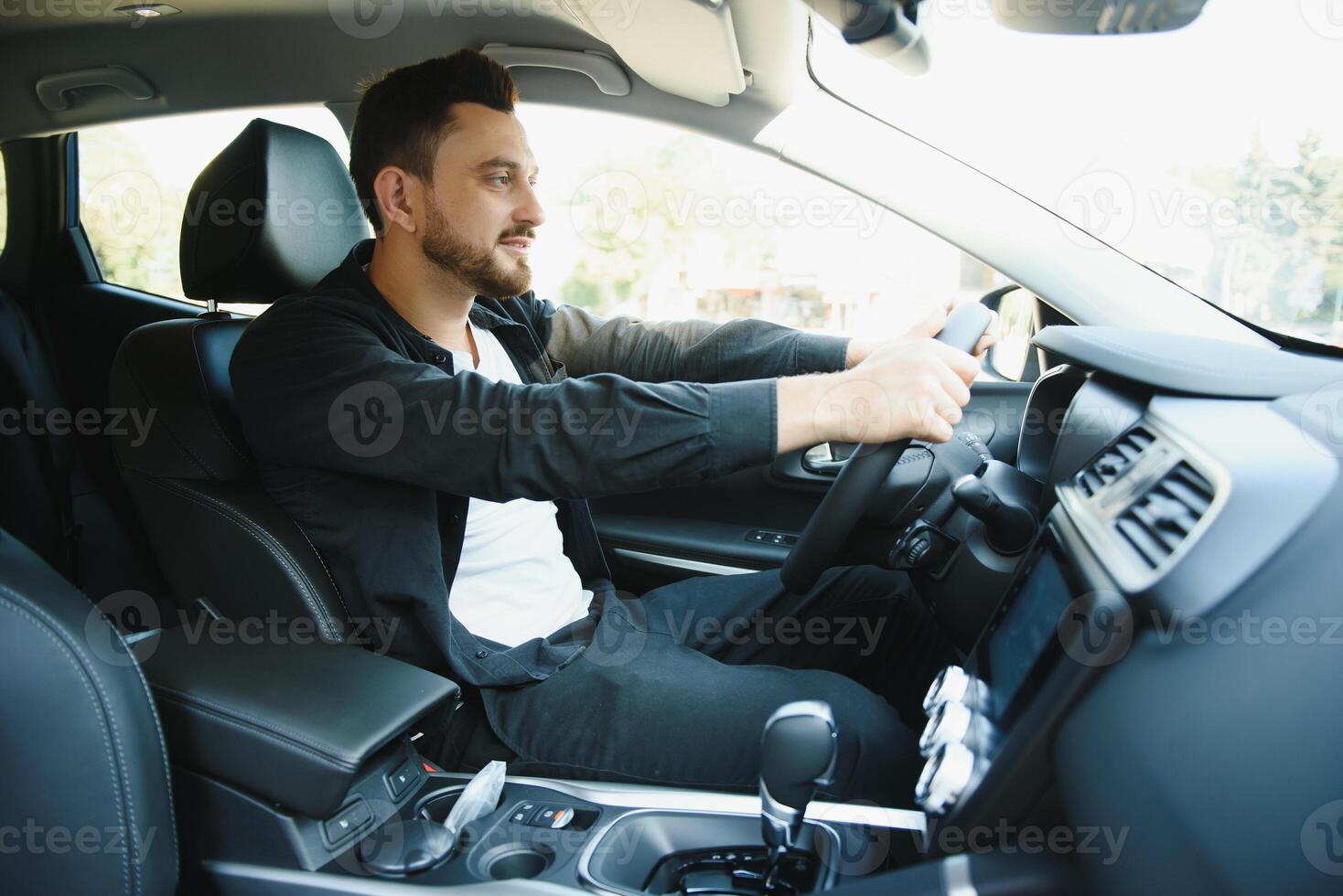 Test drive for auto. Pleasant overjoyed handsome boy holding steering wheel and driving his car while expressing gladness photo