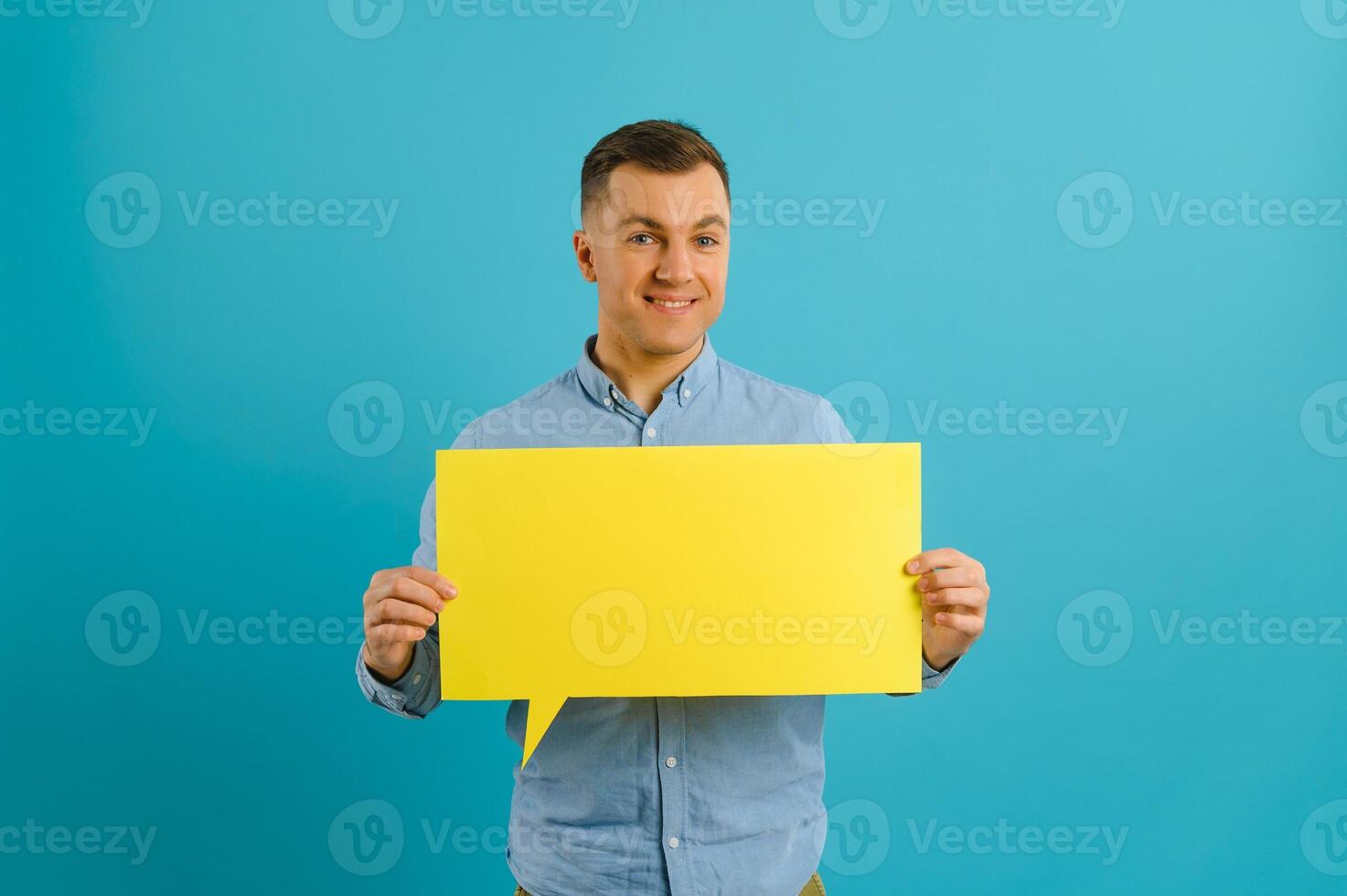 guy holding speech bubble on blue studio background, mockup for design photo