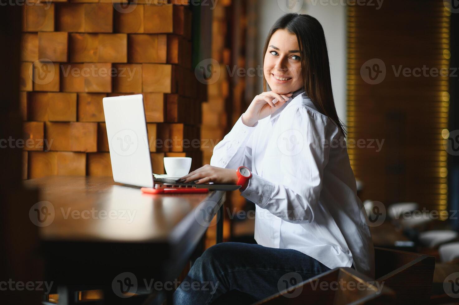 hermosa mujer caucásica soñando con algo mientras se sienta con un net-book portátil en un moderno café bar, joven y encantadora mujer independiente pensando en nuevas ideas durante el trabajo en una computadora portátil foto