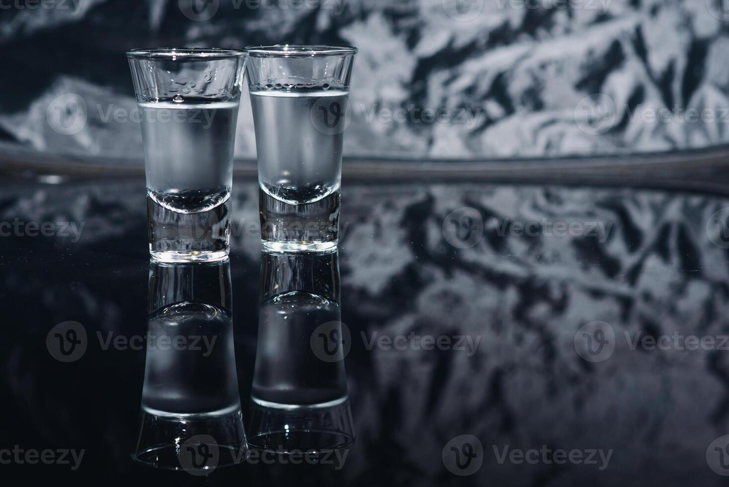 Vodka shots with ice on black table, copy space. photo