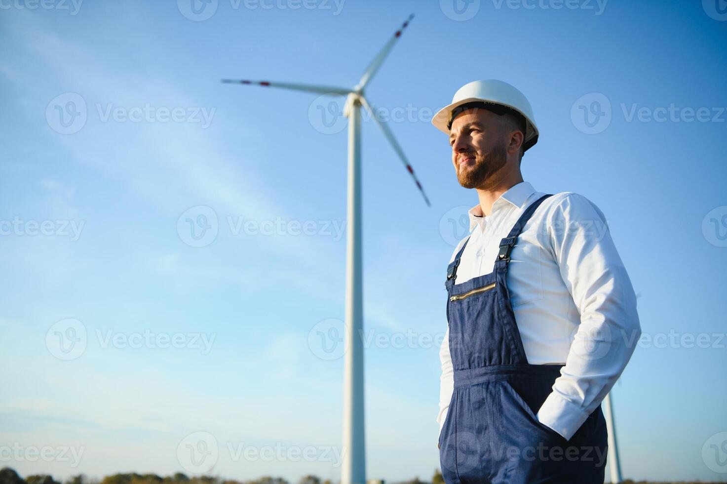 Engineer is checking energy production on wind turbine. Worker in windmills park in helmet. photo