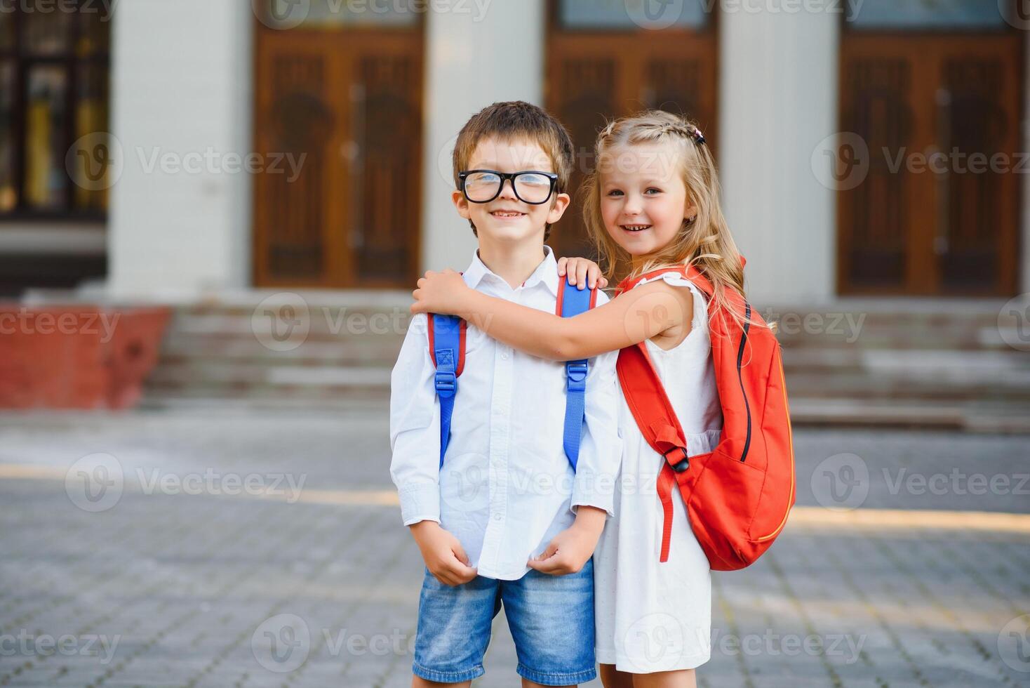 Happy children go back to school. Pupil of primary school go study with backpack outdoors. Kids go hand in hand. Beginning of lessons. First day of fall. Boy and girl from elementary student. photo