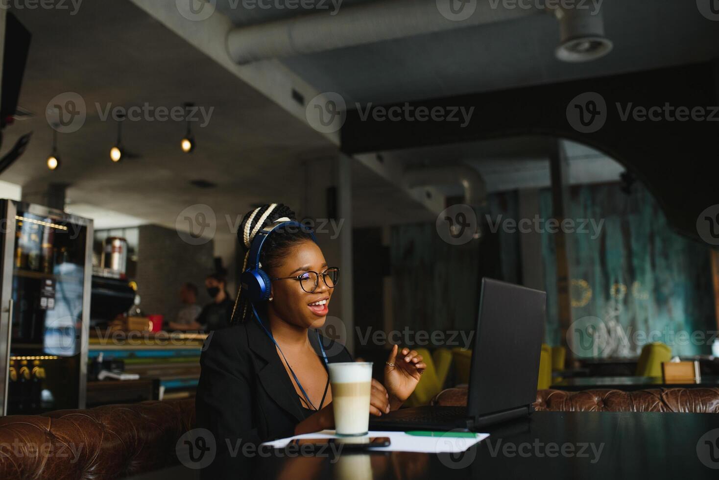 Human and technology. Young african woman typing on laptop, texting friends via social networks. Student girl browsing Internet, using free wi-fi, sitting at cafe near window on sunny day photo