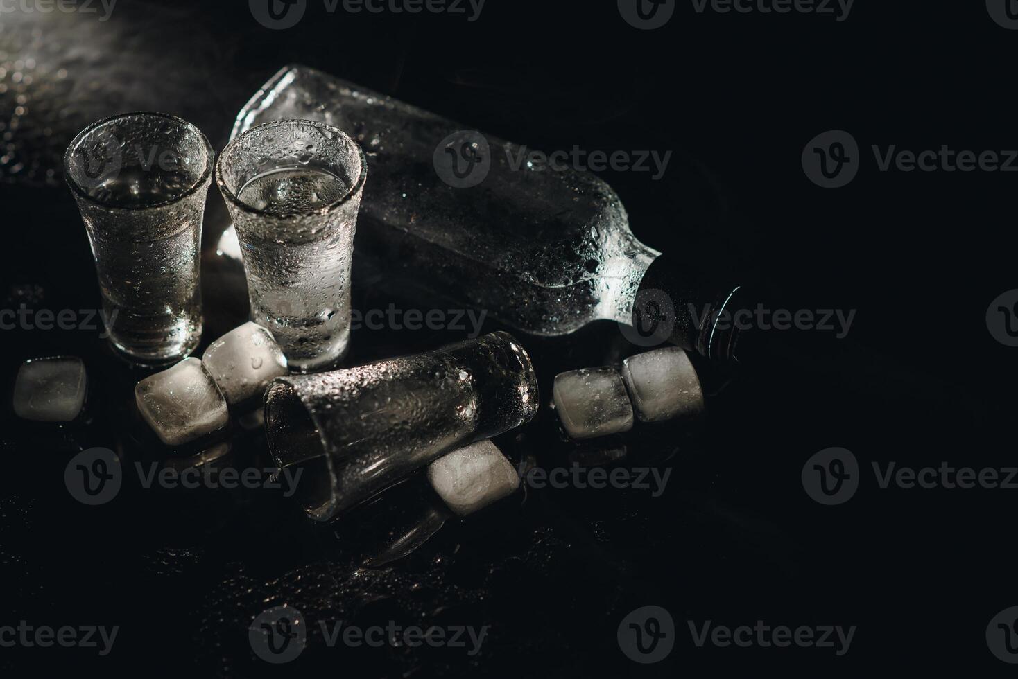 Vodka shots with ice on black table, copy space. photo