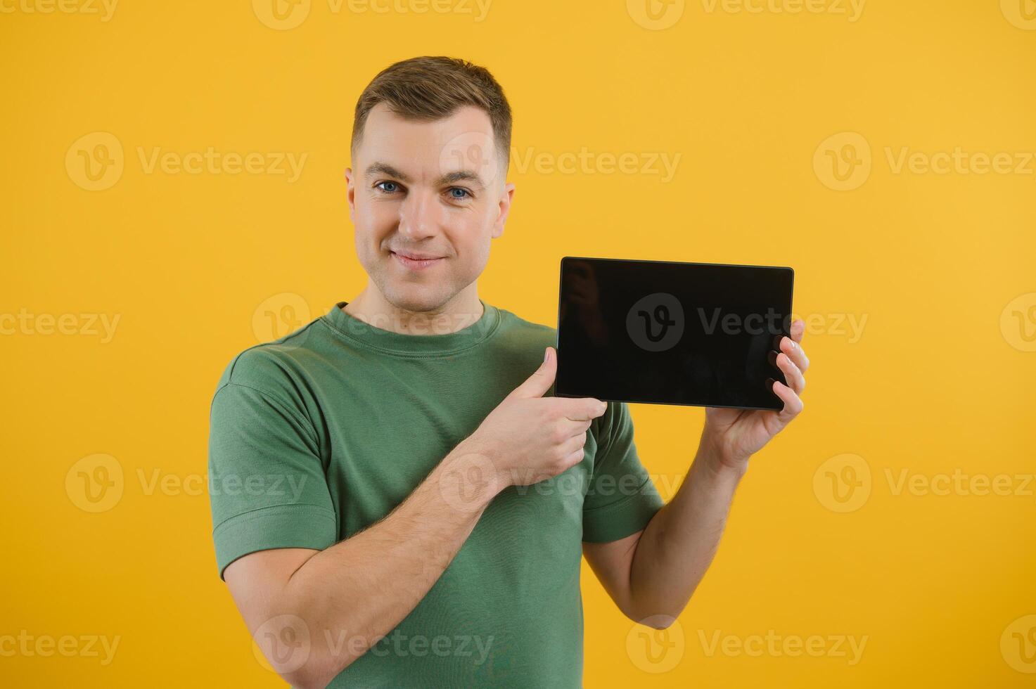 Amazed happy man using digital tablet looking shocked about social media news, astonished man shopper consumer surprised excited by online win isolated over yellow background. photo