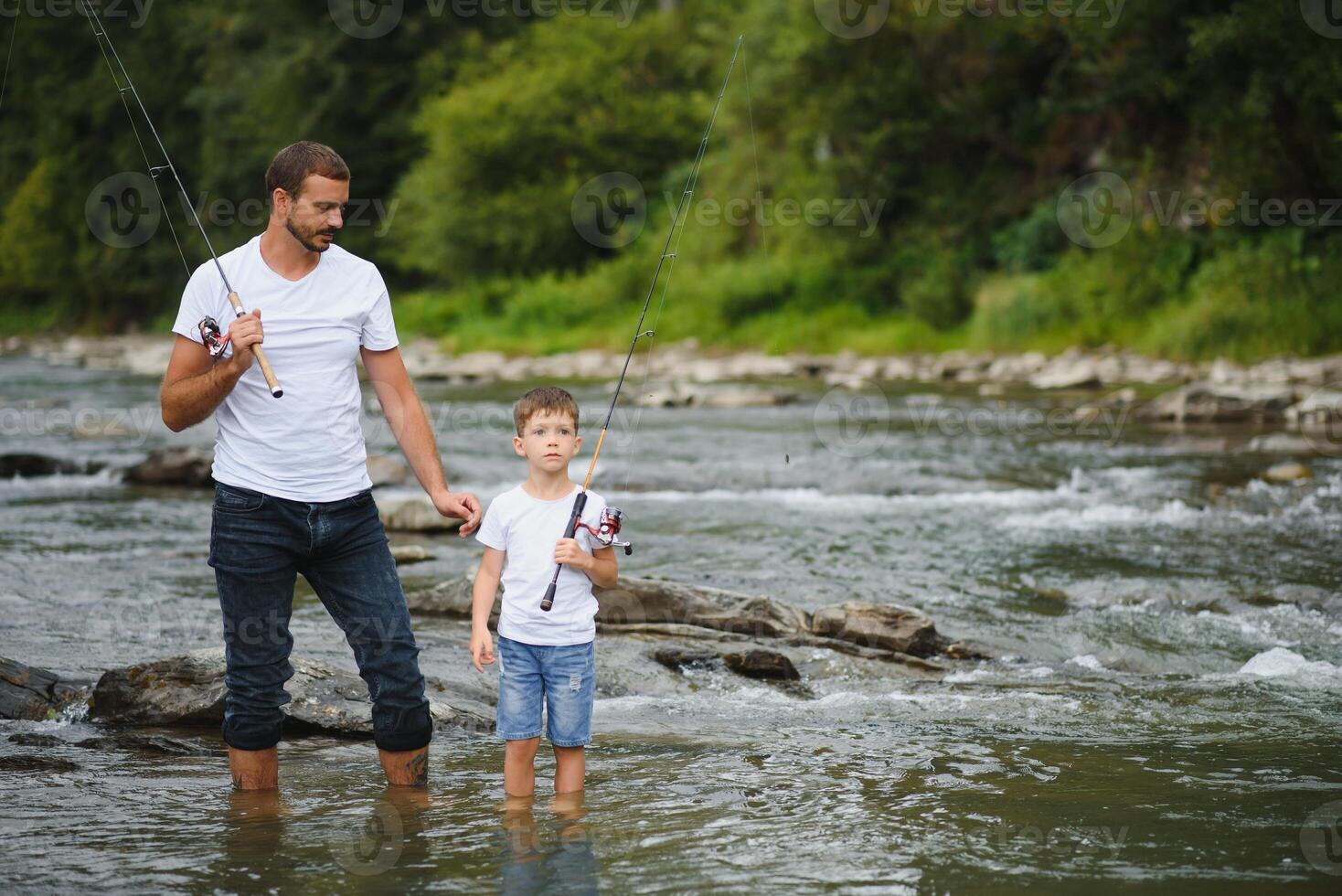 Father and son fishing. Father with his son on the river enjoying fishing holding fishing rods photo