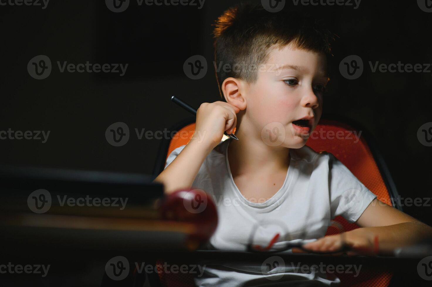 Boy learn lessons in the home setting at the table in the light of a table lamp. photo