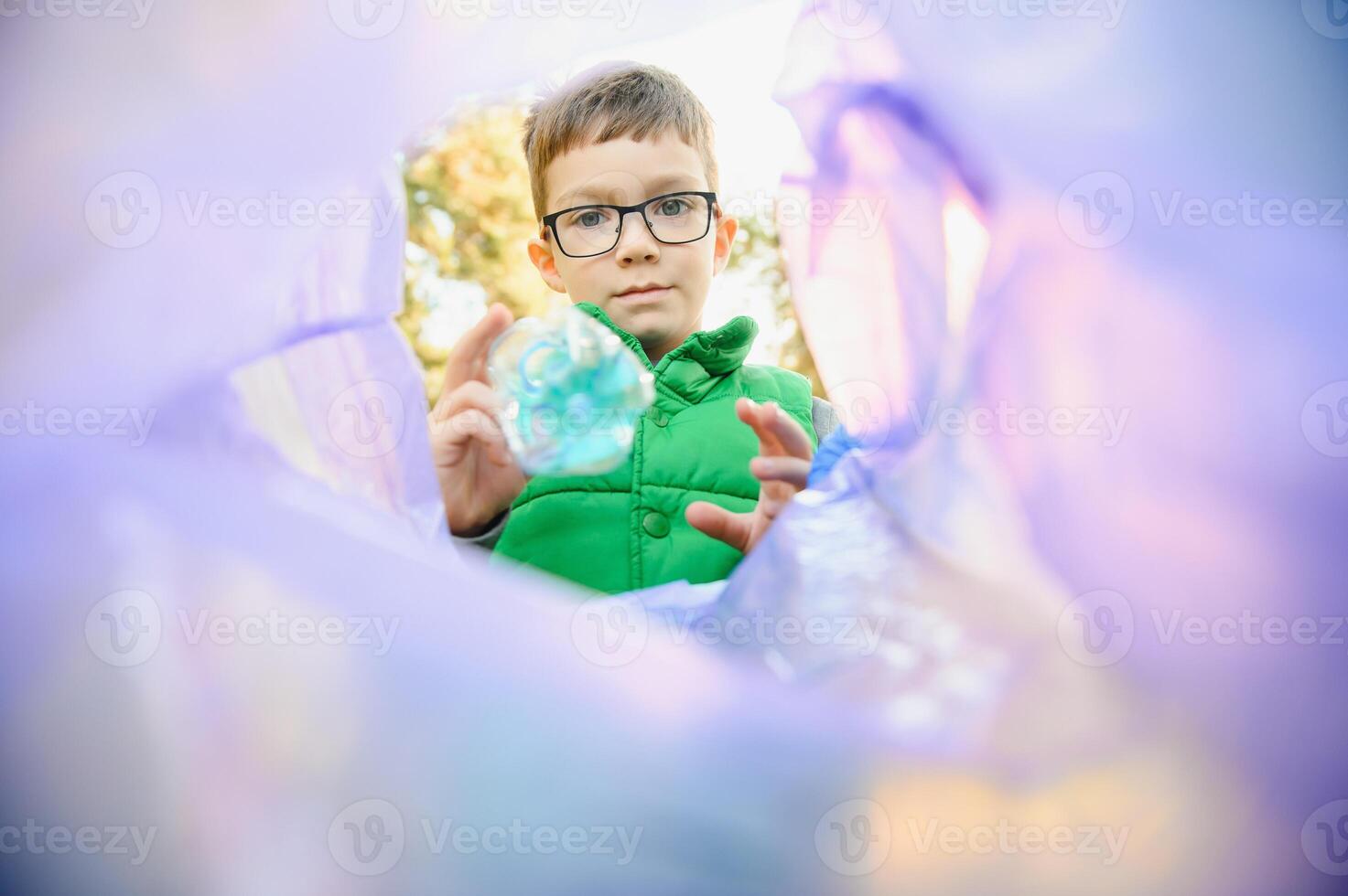 A seven-year-old boy at sunset is engaged in garbage collection in the park. Environmental care, recycling. photo