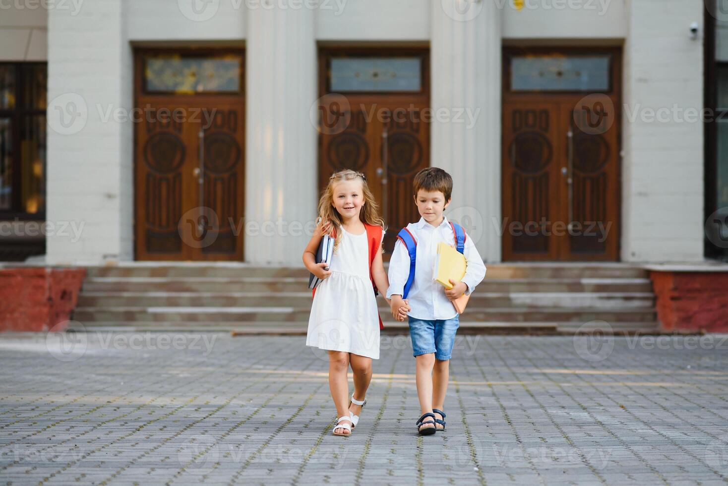 Happy children go back to school. Pupil of primary school go study with backpack outdoors. Kids go hand in hand. Beginning of lessons. First day of fall. Boy and girl from elementary student. photo