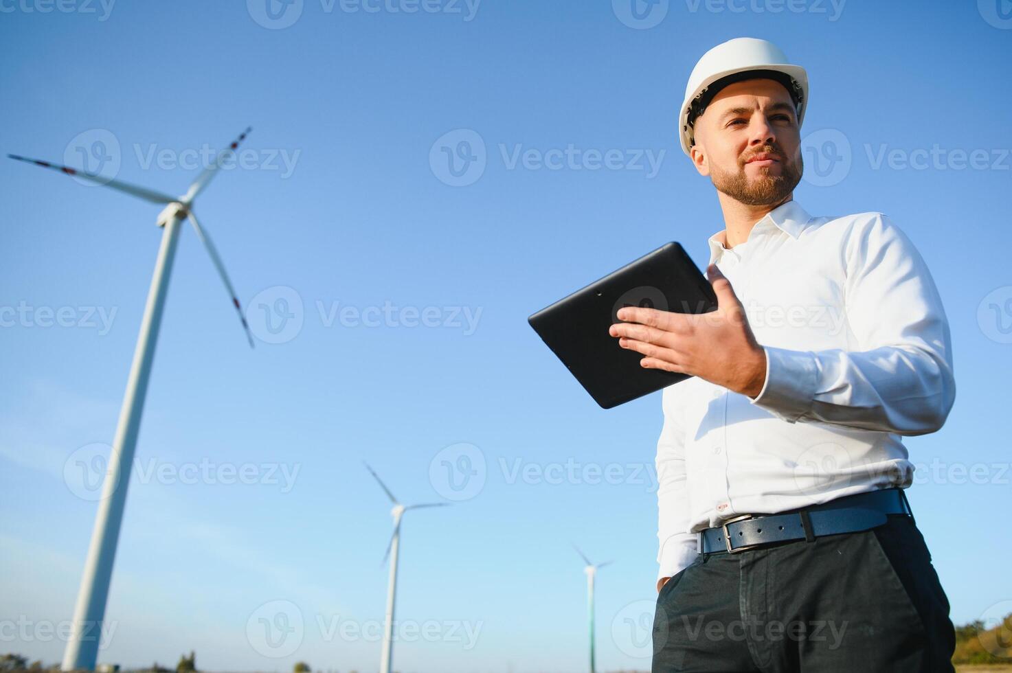 Electrical engineers working at wind turbine power generator station with laptop computer photo