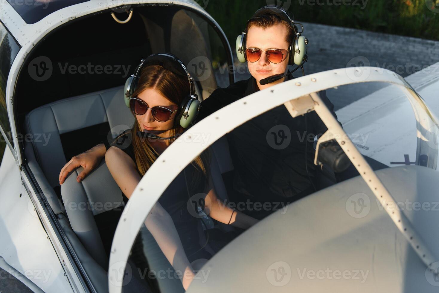 Young woman and pilot in in the cockpit of a plane. Front view photo