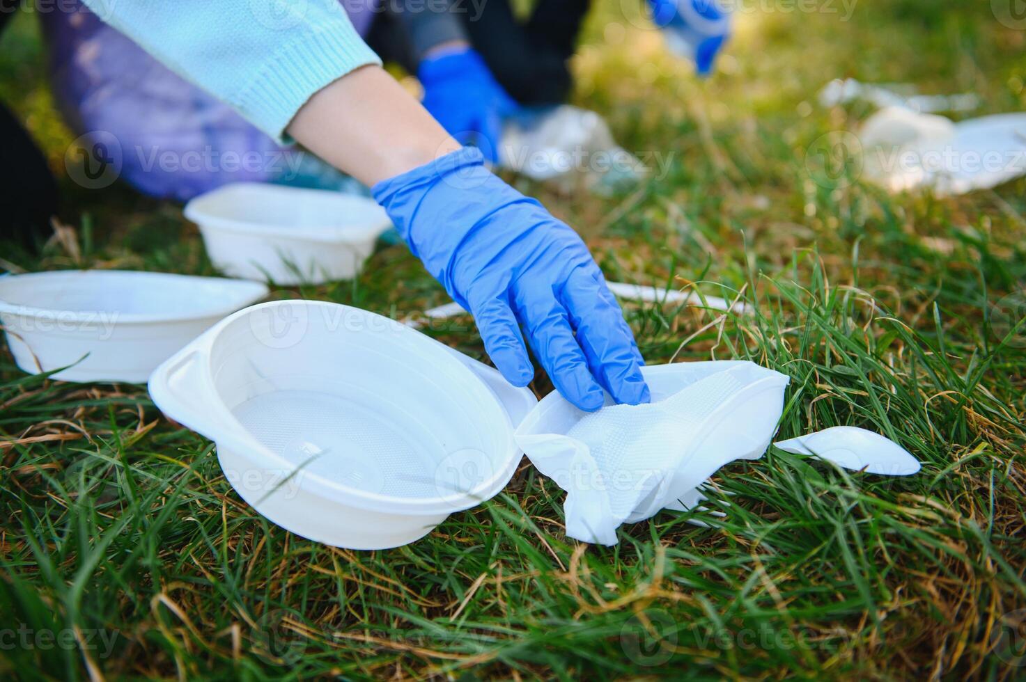 hand puts plastic debris in the garbage bag in the park photo