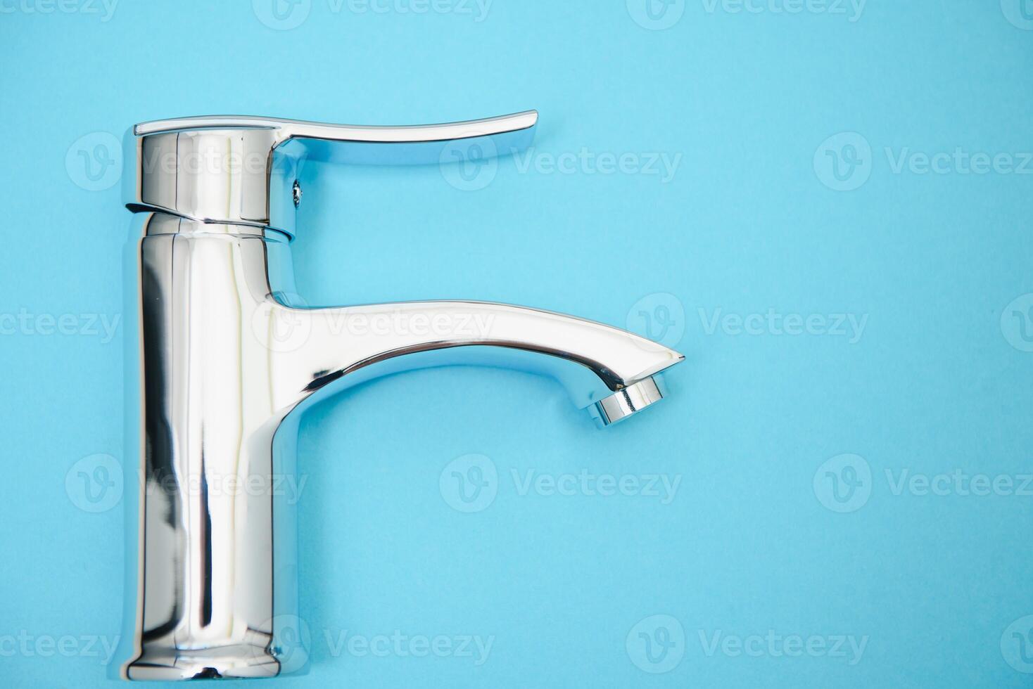 Single handle water tap on light blue background. New chrome or steel mixer tap . photo