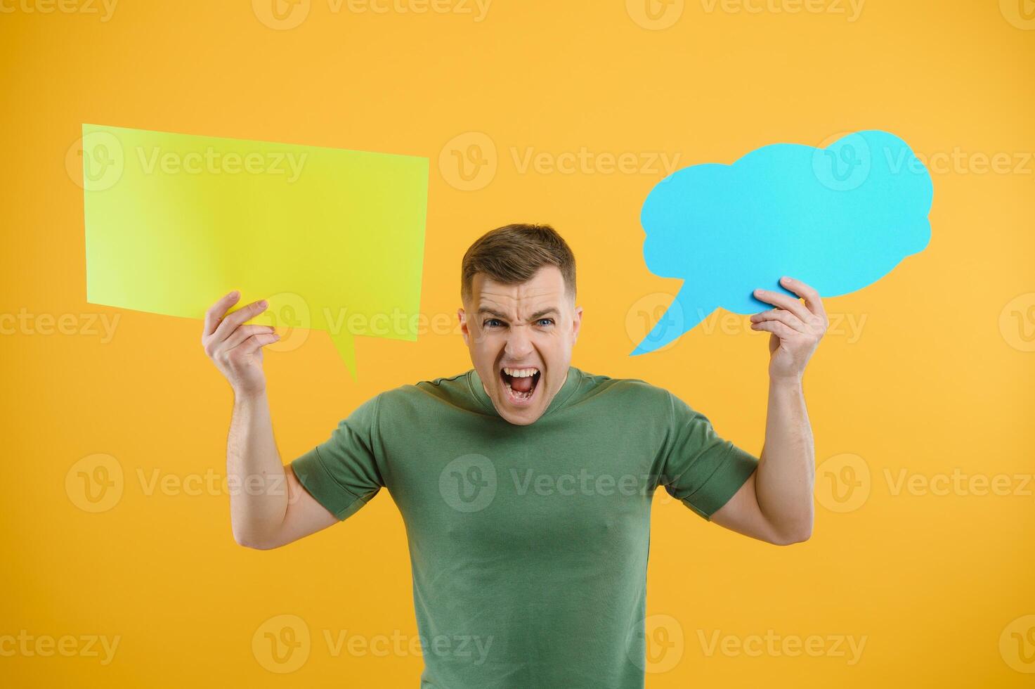 Cheerful young male pointing up and holding empty speech bubble with blank space for quote against vivid yellow background photo